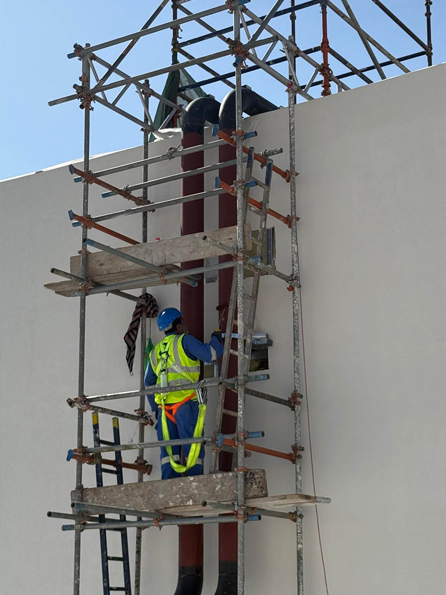 Technician working on high-level pipework from scaffolding